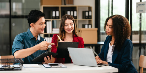 Diverse group of professionals engaging in discussion with laptop and clipboard, in bright office environment. qualified auditor report and opinion, asian people, african american, caucasian female