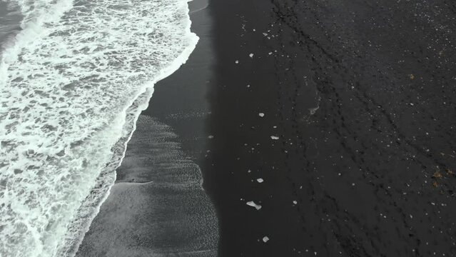 Top down aerial of diamond beach in iceland with waves and ice cubes