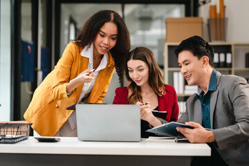 Diverse group of three professionals, two women and man, working together on design project around laptop. Product design team for industrial, working together, Asian man, African american people