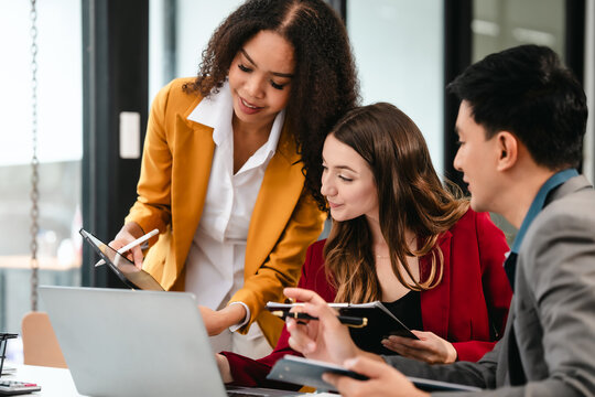 Diverse group of three professionals, two women and man, working together on design project around laptop. Product design team for industrial, working together, Asian man, African american people