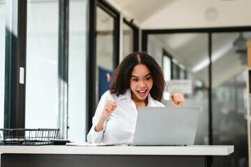 African American businesswoman, focused on her work on a laptop, possibly managing industrial...