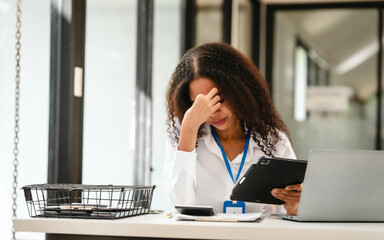 Obraz premium African American businesswoman at her desk, looking stressed and troubled, possibly over a challenging issue at work.
