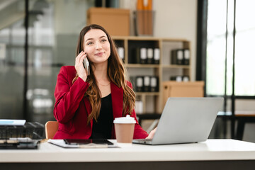 Caucasian businesswoman, likely an accountant or CPA, smiling and holding a coffee cup while working on her laptop.