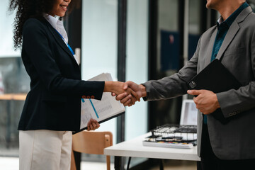 Confident Asian businessman and African American businesswoman reviewing and discussing UX/UI design elements together at desk. in formal suit