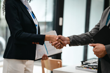 Fototapeta premium Confident Asian businessman and African American businesswoman reviewing and discussing UX/UI design elements together at desk. in formal suit