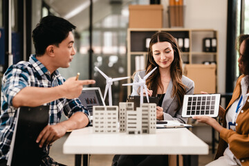 Diverse team with Asian man, African American woman, Caucasian woman discussing a clean energy city planning project with building models and solar panels.