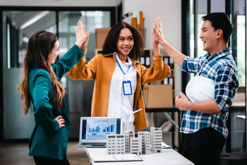 Diverse team with Asian man, African American woman, Caucasian woman discussing a clean energy city planning project with building models and solar panels.
