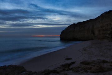 Sandy beach with a cliff in southern Portugal on a winter evening during blue hour.