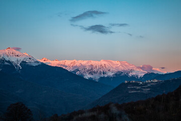 Sunlight cover the mountain peaks covered with snow. Scenic evening in the mountains