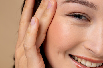 Portrait of caucasian woman with brown hair wearing natural makeup on beige background