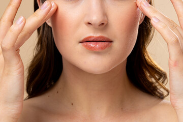 Fototapeta premium Caucasian woman with brown hair wearing natural makeup on beige background