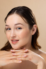 Portrait of caucasian woman with brown hair wearing natural makeup on beige background