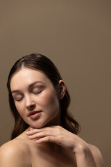 Caucasian woman with brown hair wearing natural makeup on beige background, copy space