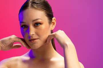 Caucasian woman wearing golden eye shadow and lipstick on purple background, copy space