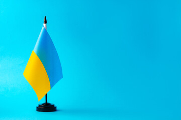 Small flag of Ukraine on blue background