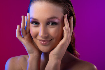 Fototapeta premium Portrait of caucasian woman wearing purple eye shadow on purple background