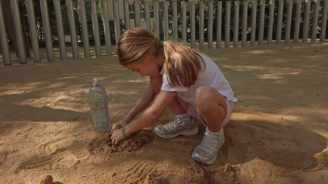 Little girl playing in a playground, making constructions with sand and water