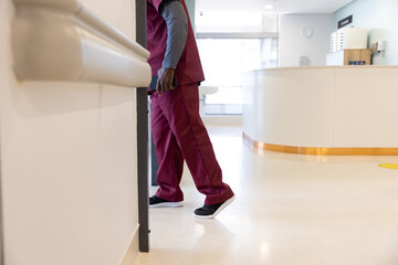 Lowsection of african american male doctor walking in hospital corridor - Powered by Adobe
