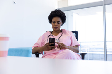 African american female doctor using smartphone in hospital office