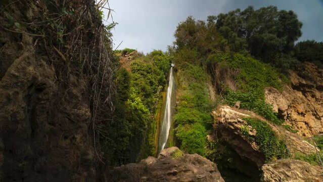 Beautiful waterfall and green rocky surroundings, time lapse