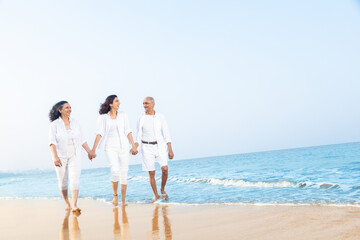 Happy senior indian couple with beautiful young daughter enjoying vacation at beach.