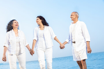 Happy senior indian couple with beautiful young daughter walking and enjoying vacation at beach....