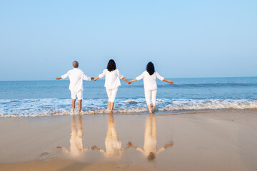 Happy senior indian couple with beautiful young daughter posing and enjoying vacation at beach.