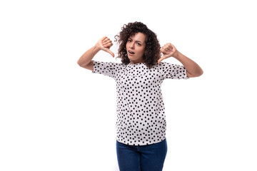 young surprised well-groomed brunette curly woman dressed in a polka dot print blouse