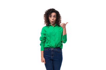 young slender brunette woman with curly hair in a green shirt points with her hand