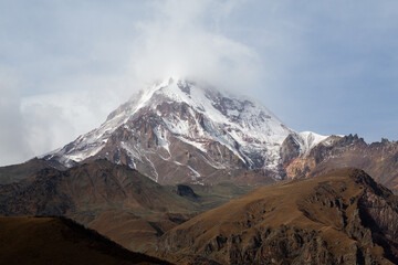 View of Mount Kazbek from the city of Stepantsminda in Georgia in good climbing weather. This is a dormant stratovolcano and one of the largest mountains in the Caucasus.