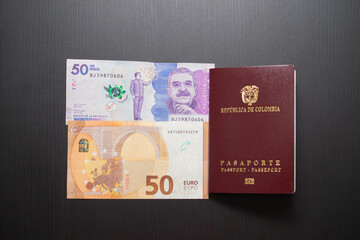 top shot of a 50 euro bill with a 50,000 colombian peso bill and the colombia passport showing the concept of international travel, currency exchange and economy