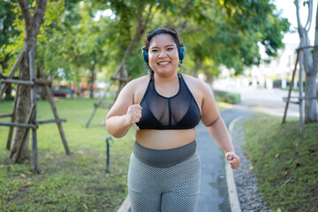 Plus size asian woman running in a park for health, wellness and outdoor exercise. Nature, sports...