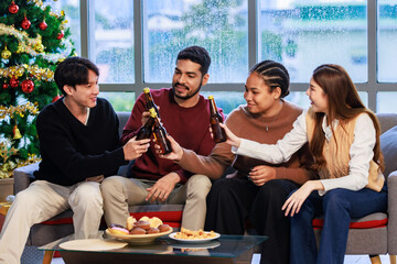 Millennial Asian Indian multinational cheerful male female friends celebrating Merry Christmas Eve Happy New Year  cheers toasting beers in living room full festival decoration with Xmas tree