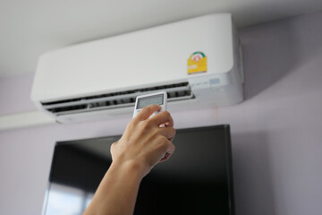 Fototapeta premium Hand hold remote control directed on the air conditioner