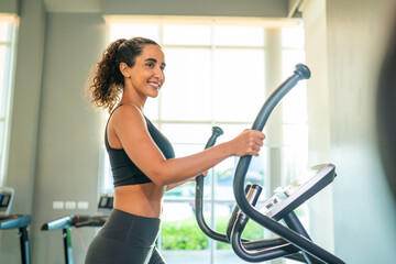 Fitness exercising in gym. Sporty woman in a sports bra doing exercise by running on treadmill during a workout at the gym fitness center with group of people.