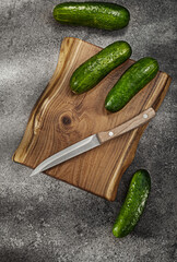 Cucumbers And Kitchen Knife On Vintage Chopping Board.