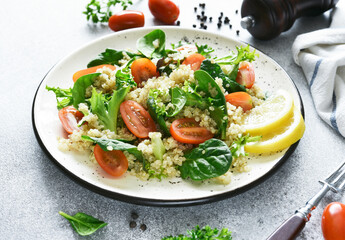 Salad with quinoa tomatoes and spinach on a light background