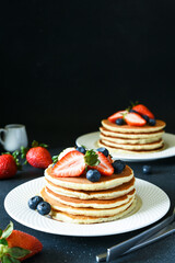 Pancakes with berries for breakfast on a dark background