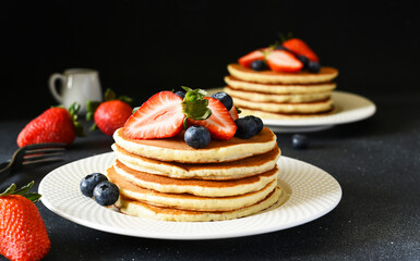 Pancakes with berries for breakfast on a dark background