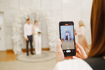 A young woman is filming a wedding ceremony at the registry office. 