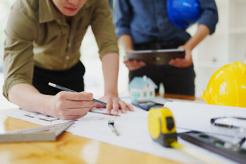 multi ethnic engineer brainstorming and measuring for cost estimating on blueprint and floor plan drawings about design architectural and engineering for houses and buildings