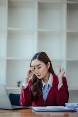 Fototapeta premium Asian woman stressed while working on laptop Tired Asian businesswoman has a headache at the office feeling sick at work