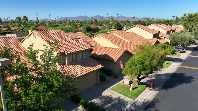 Southwest USA neighborhood Aerial view of terracotta roof homes, green trees, with mountains in the background.