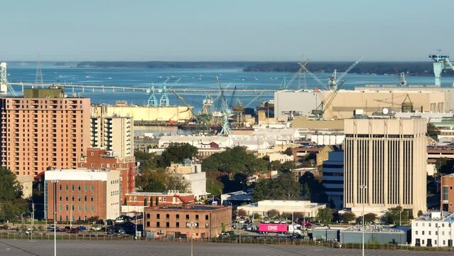 Newport News, Virginia skyline. Aerial panning shot of buildings, shipping yards, and James River.