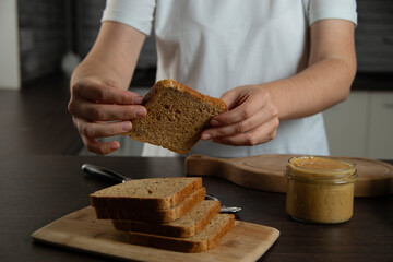 Woman preparing breakfast. Bread with peanut butter.