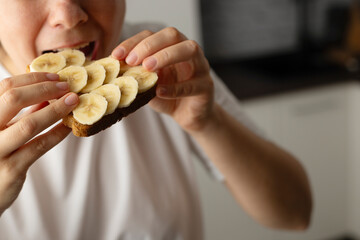 Eating sandwich with peanut butter and banana. American breakfast concept.