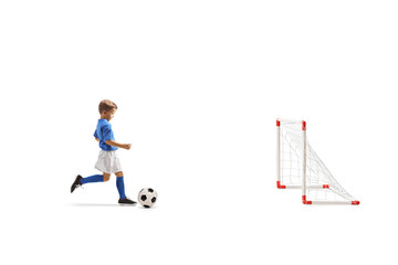 Full length profile shot of a boy with soccer ball running towards a goal