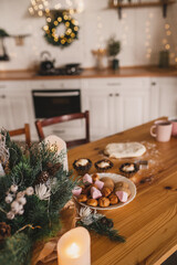 Homemade Christmas cookies on a decorated wooden table in the kitchen. Raw dough, muffin tins, chocolate chip cookies are prepared before Christmas by the whole family