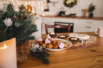 Homemade Christmas cookies on a decorated wooden table in the kitchen. Raw dough, muffin tins, chocolate chip cookies are prepared before Christmas by the whole family