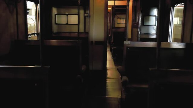 Walking in slow-motion in the past, into an empty passenger train's cabin from the 1960s. Nobody is inside.
